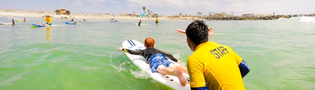 Photo of a YMCA staff member pushing a surf student on a surfboard