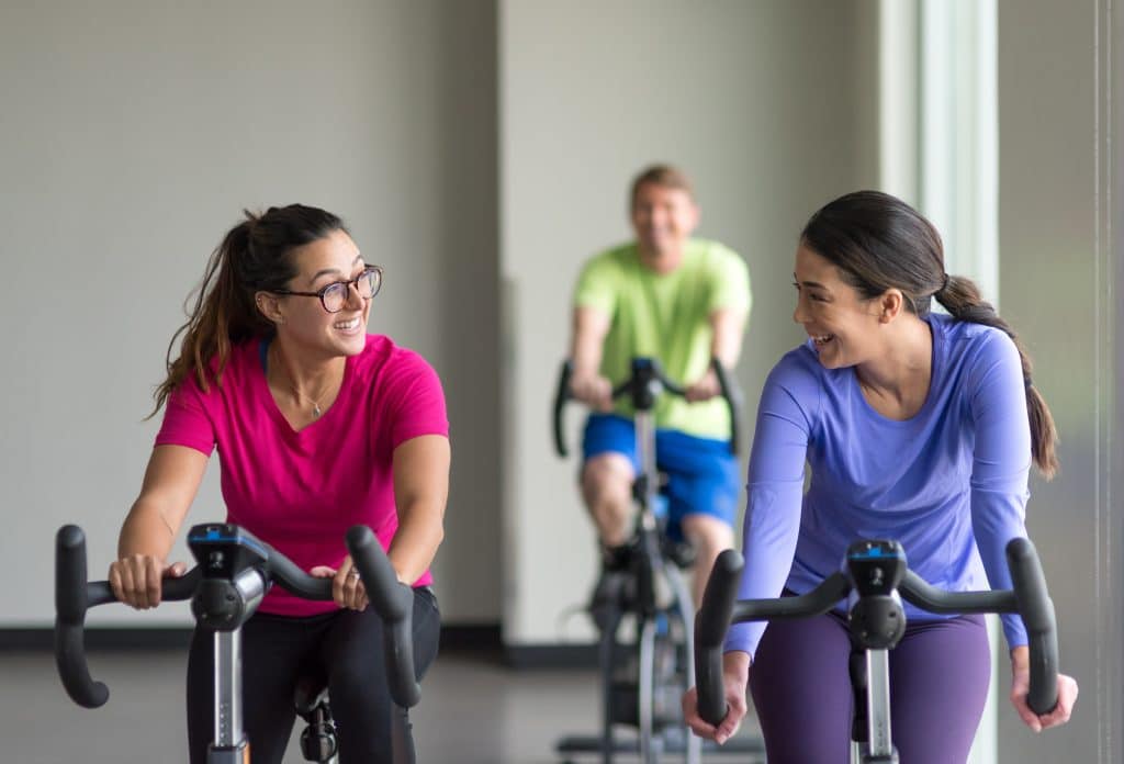 women cycling on bike in group ex class