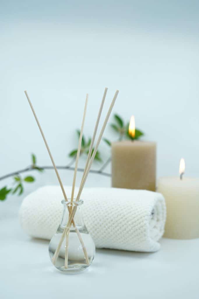 diffuser, towel and candles on a table