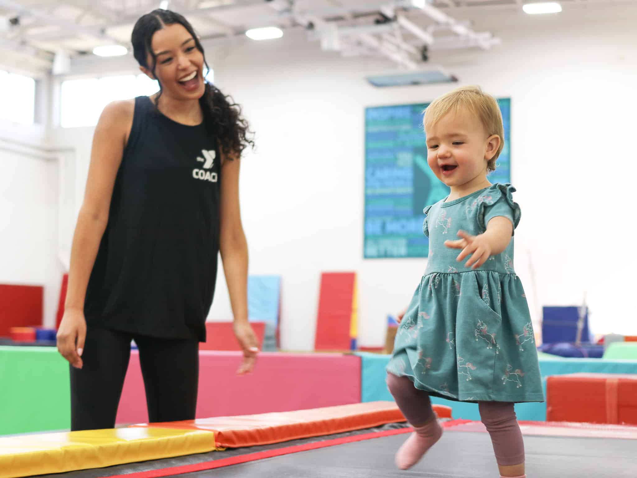 child playing in gymnastics center with coach