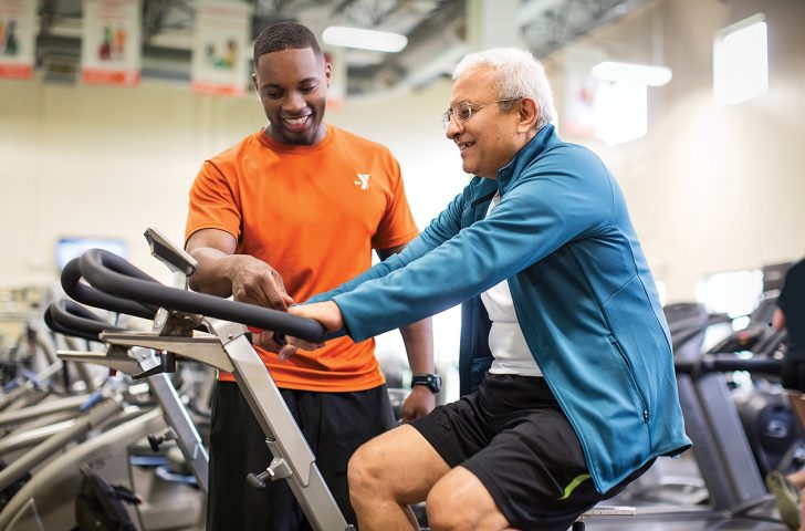 staff person showing member how to use exercise machine